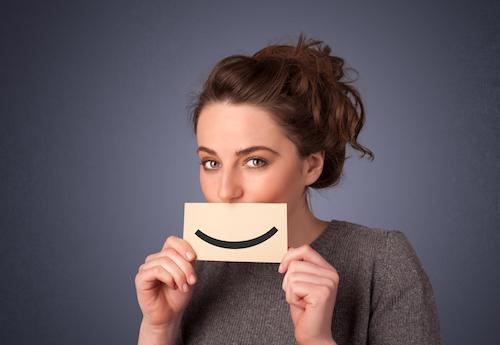 woman holding a picture of a smile over her mouth