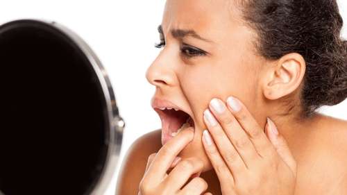 A woman checking her teeth after her dental crown fell off in Colorado Springs, CO