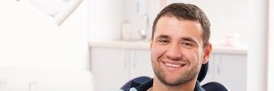 Man smiling in dental chair after treatment in Colorado Springs