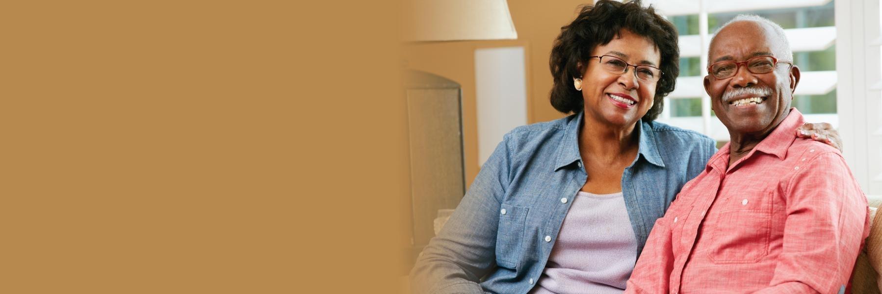 older couple smiling while sitting on couch